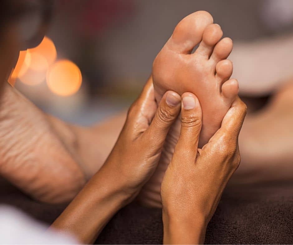Photo massage des pieds avec deux mains sur le pied droit massage assis